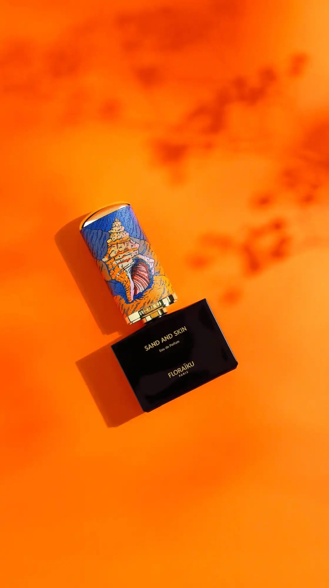 A blue and gold patterned lipstick tube alongside a black compact.